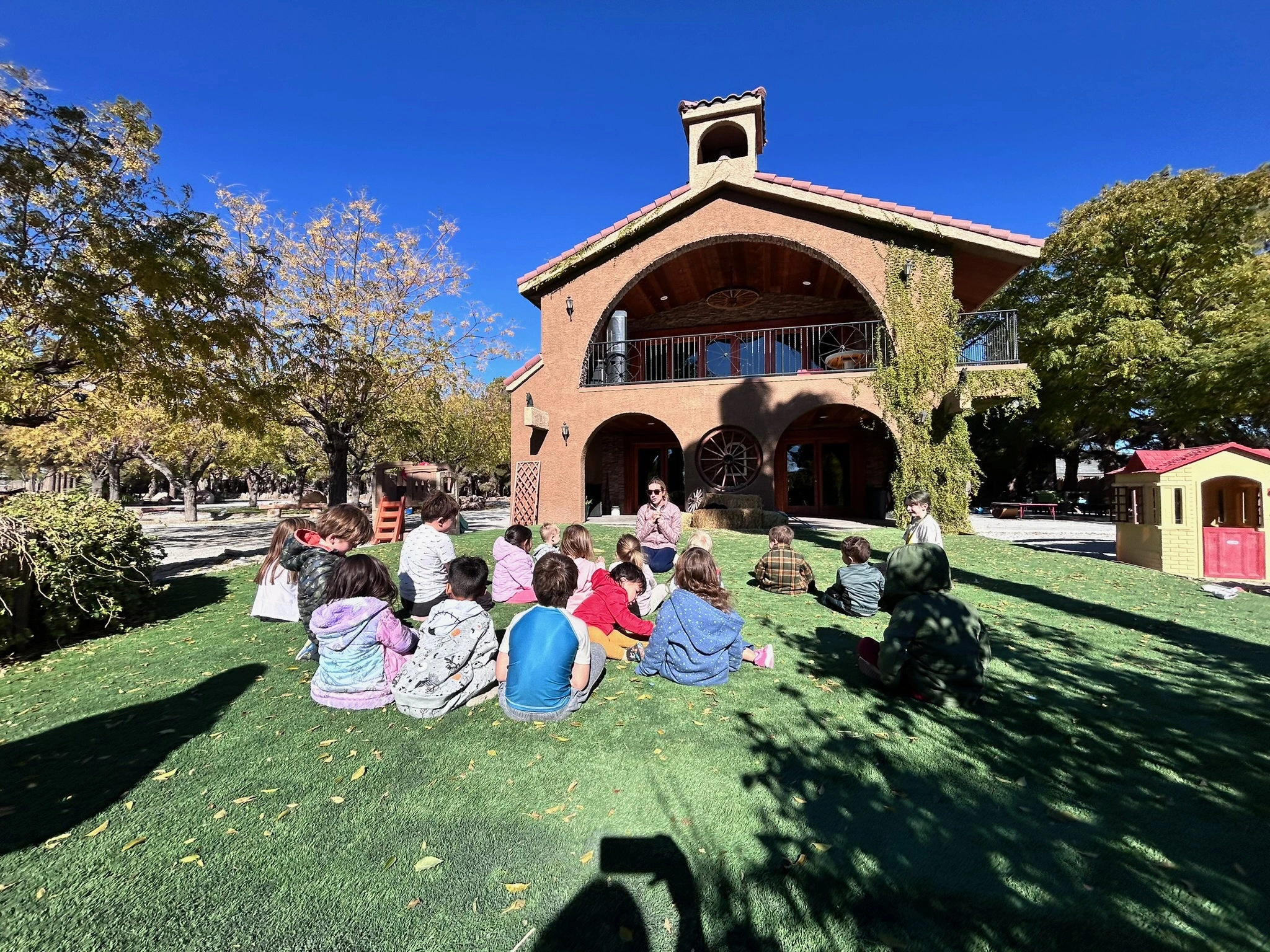 Children learning outdoors at Montessori Skye View Learning Center with teacher on sunny day - beautiful outdoor learning environment